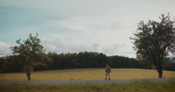 度假时 年轻的女探险家在森林里的草地上与多云的天空同行 — 图库视频影像