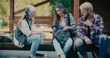 Genç bir kadın turist arkadaşlarıyla bankta oturuyor.