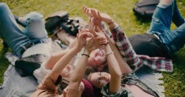 Parkta battaniyeye uzanmış el ele tutuşan mutlu arkadaşlar.