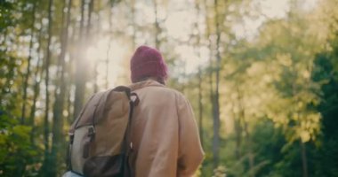Sırt çantalı genç bir turist tatil sırasında ormanda yürüyüş yapıyor.