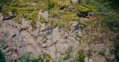 Genç bayan yürüyüşçü ormandaki bitkilerin arasında kayalık yüzeye yakın duruyor.