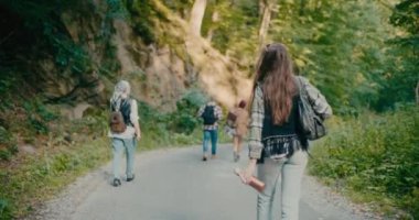 Genç bir kadın, erkek ve kadın turistlerle birlikte ormanda yürüyüş yapıyor.