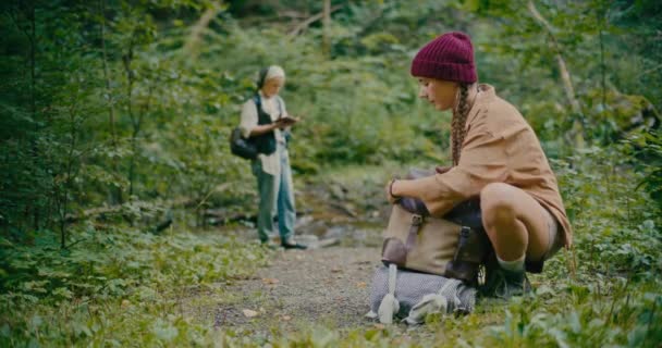 Woman Wearing Knit Hat Packing Backpack While Crouching Plants Forest — Stock Video