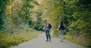 Kaygısız erkek ve dişi turistler ormanda ağaçların arasında yürürken ormanı keşfediyorlar.