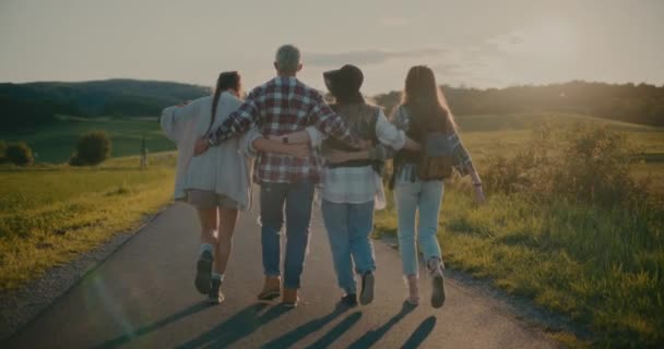 メドウ近くの徒歩道を歩き回る腕を持ったケアフリーの男性と女性の友人 — ストック動画