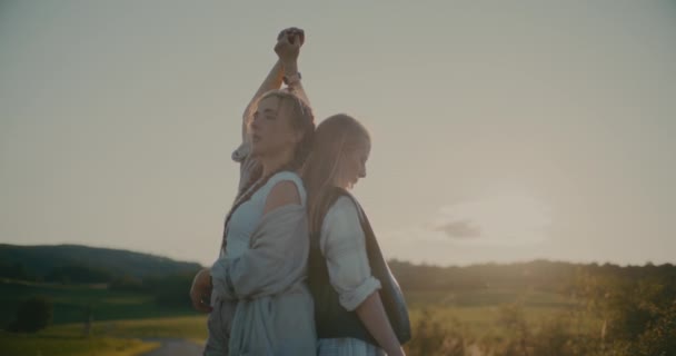 Genç Bayan Arkadaşlar Ele Tutuşurken Birlikte Gökyüzüne Karşı Çayırda Dururlar — Stok video