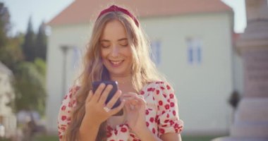 Mutlu sarışın kadın hafta sonu bahçede cep telefonu kullanıyor.