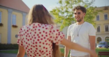 Gülümseyen genç adam bahçede onu selamlarken kız arkadaşına sarılıyor.