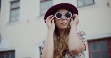 Güzel sarışın kadın, şehirde bina karşısında dikilirken son moda güneş gözlüğü takıyor.