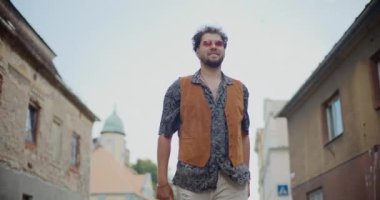 Evlerin arasında yürürken ve hafta sonları eğlenirken mutlu genç adam dans ediyor.