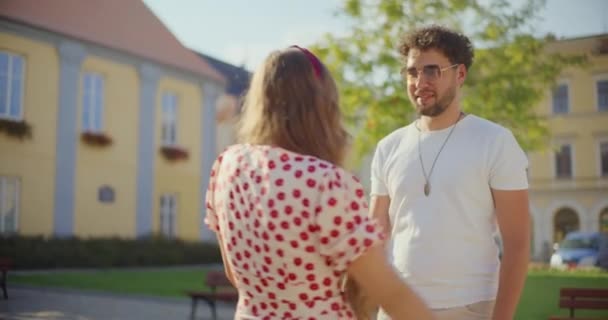 公園で彼に挨拶しながらボーイフレンドを受け入れる金髪の女性のリアビュー — ストック動画