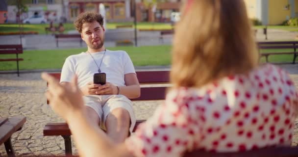 Mladý Muž Pomocí Chytrý Telefon Mluvit Přítelkyní Zatímco Sedí Lavičce — Stock video