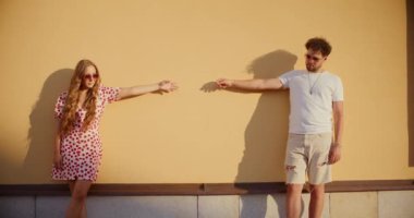 Heteroseksüel çift duvara yaslanırken el kol hareketi yapıyor.