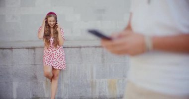 Cep telefonuyla konuşan mutlu bir kadın. Duvarın önünde duran bir adam var.