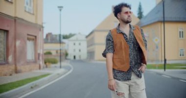Genç adam modaya uygun kıyafetler giyiyor ve hafta sonu şehirde yürürken etrafa bakıyor.
