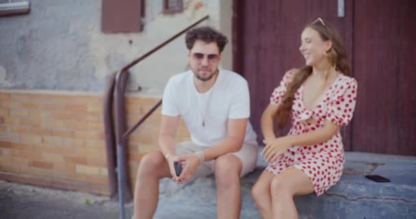 Szczęśliwa Heteroseksualna Para Śmieje Się Siedząc Naprzeciw Drzwi Podczas Weekendu — Wideo stockowe