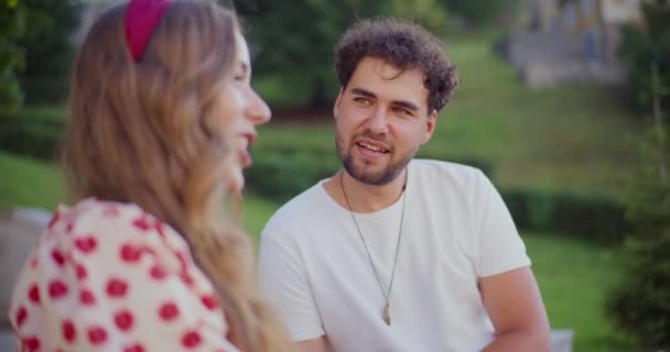 ブロンドの若い女性は 庭で余暇の時間を過ごしながら男性の友人と話す — ストック動画