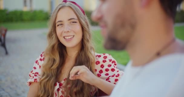 ハッピーブロンドの若い女性は週末に公園でボーイフレンドによって歌います — ストック動画