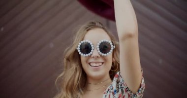 Hafta sonunun keyfini çıkarırken şapka ve güneş gözlüğü takan neşeli sarışın kadın.