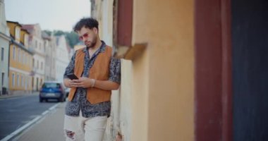 Yakışıklı genç adam akıllı telefondan mesaj yolluyor. Yaya yolunda duruyor.