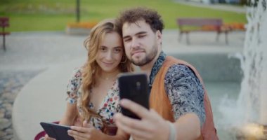 Yakışıklı adam tatilde kız arkadaşıyla cep telefonundan selfie çekiyor.