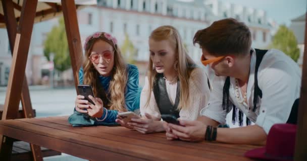 週末にテーブルでスマートフォンを使用する若い男性と女性の友人 — ストック動画