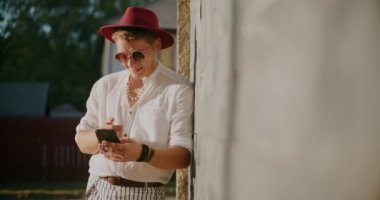 Güneşli bir günde cep telefonundan duvardan duvara gülümseyen yakışıklı bir adam.