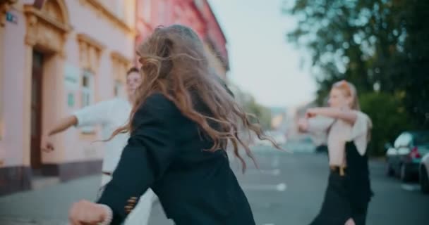 Bonne femme blonde aime danser avec des amis masculins et féminins en ville pendant le week-end