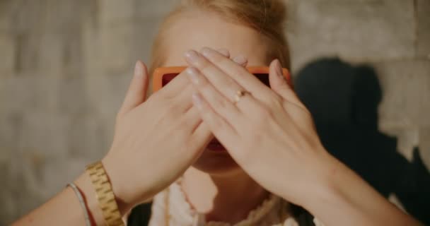 Kvinna Bär Solglasögon Och Skärmande Ögon Från Solljus Mot Vägg — Stockvideo