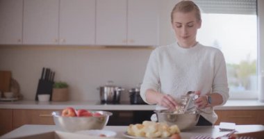 Mutfaktaki kadın elmalı pasta için elma soyuyor.