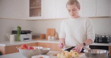 Mutfaktaki kadın elmalı pasta için elma soyuyor.
