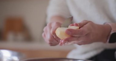 Mutfaktaki kadın elmalı pasta için elma soyuyor.