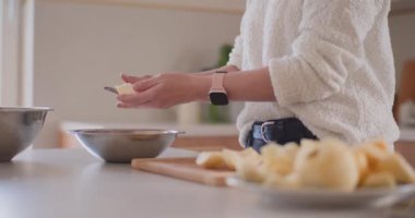 Mutfaktaki kadın elmalı pasta için elma soyuyor.