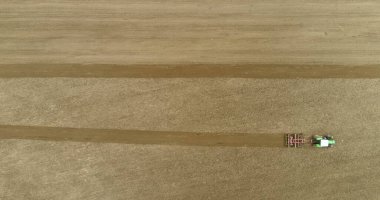 Çekici tarlanın havadan görünüşü çiftçilik arka planının çok üstünde. Çiftçi Harrows 'u kullanıyor ve tarla sürüyor. Zirai tarlaları süren ağılları kapatın..