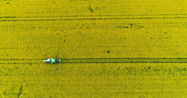 Agriculture Aerial Of Tractor Spraying Farm Land With Pesticides, agricultural chemicals. Drone shoot of farming Equipment. Food Modification GMO Farming Concept.
