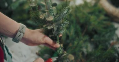 Noel süslerini hazırlayan kadın manzarası. Noel tatili için çelenk hazırlayan kadın. Atölyede Noel Çelengi Yaratan Çiçekçi.