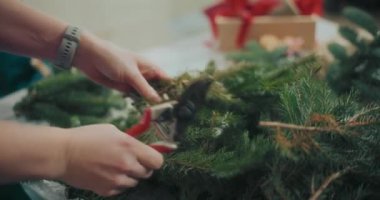 Noel süslerini hazırlayan kadın manzarası. Noel tatili için çelenk hazırlayan kadın. Atölyede Noel Çelengi Yaratan Çiçekçi.