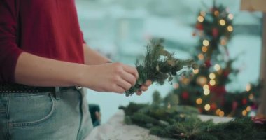 Noel süslerini hazırlayan kadın manzarası. Noel tatili için çelenk hazırlayan kadın. Atölyede Noel Çelengi Yaratan Çiçekçi.