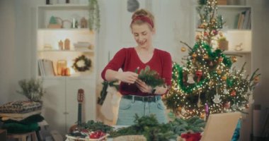 Noel süslerini hazırlayan kadın manzarası. Noel tatili için çelenk hazırlayan kadın. Atölyede Noel Çelengi Yaratan Çiçekçi.