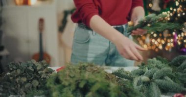 Noel süslerini hazırlayan kadın manzarası. Noel tatili için çelenk hazırlayan kadın. Atölyede Noel Çelengi Yaratan Çiçekçi.