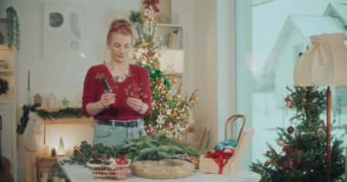 Noel süslerini hazırlayan kadın manzarası. Noel tatili için çelenk hazırlayan kadın. Atölyede Noel Çelengi Yaratan Çiçekçi.