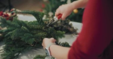 Noel süslerini hazırlayan kadın manzarası. Noel tatili için çelenk hazırlayan kadın. Atölyede Noel Çelengi Yaratan Çiçekçi.
