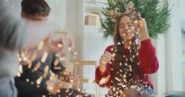 Işıkları yanan mutlu genç adam ve kadın Noel tatili boyunca evde oturuyor.
