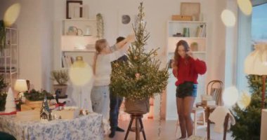 Genç adam ve kadınlar oturma odasında Noel ağacını ışık ve süs ile süslüyorlar.