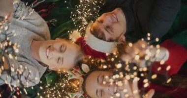 Evlerinde birbirine dolanmış parlak ışıkları olan mutlu erkek ve kadınların fotoğraflarının tam üstünde.