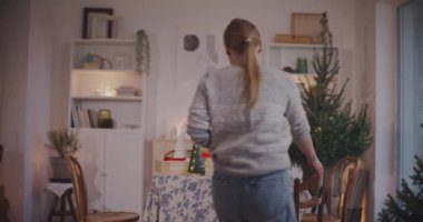 Genç bir kadın evdeki oturma odasında Noel çoraplarını masaya koyuyor.
