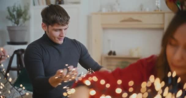 Mladý Muž Třídění Zamotané Osvětlené Světla Kamarádkami Doma Během Vánoc — Stock video