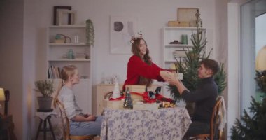 Genç bir kadın tatilde erkek ve bayan arkadaşlara Noel hediyeleri veriyor.