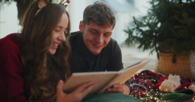 Mutlu heteroseksüel çift Noel tatilinde evde birlikte fotoğraf albümü izliyor.