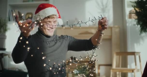 Χαμογελαστή Άνθρωπος Φορώντας Καπέλο Σάντα Φωτισμένα Φώτα Για Χριστουγεννιάτικη Διακόσμηση — Αρχείο Βίντεο